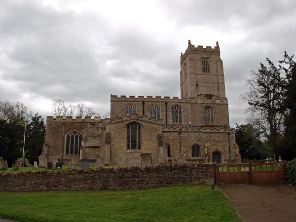 a picture of the church, fronted by a low stone wall and double wooden gates at Glatton